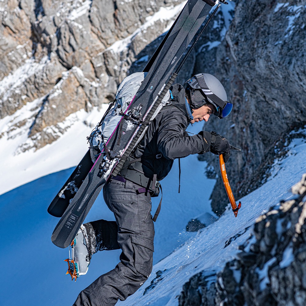 Skieur avec ses skis accroché au sac Mountain 35 litres en train de progresser en montagne.