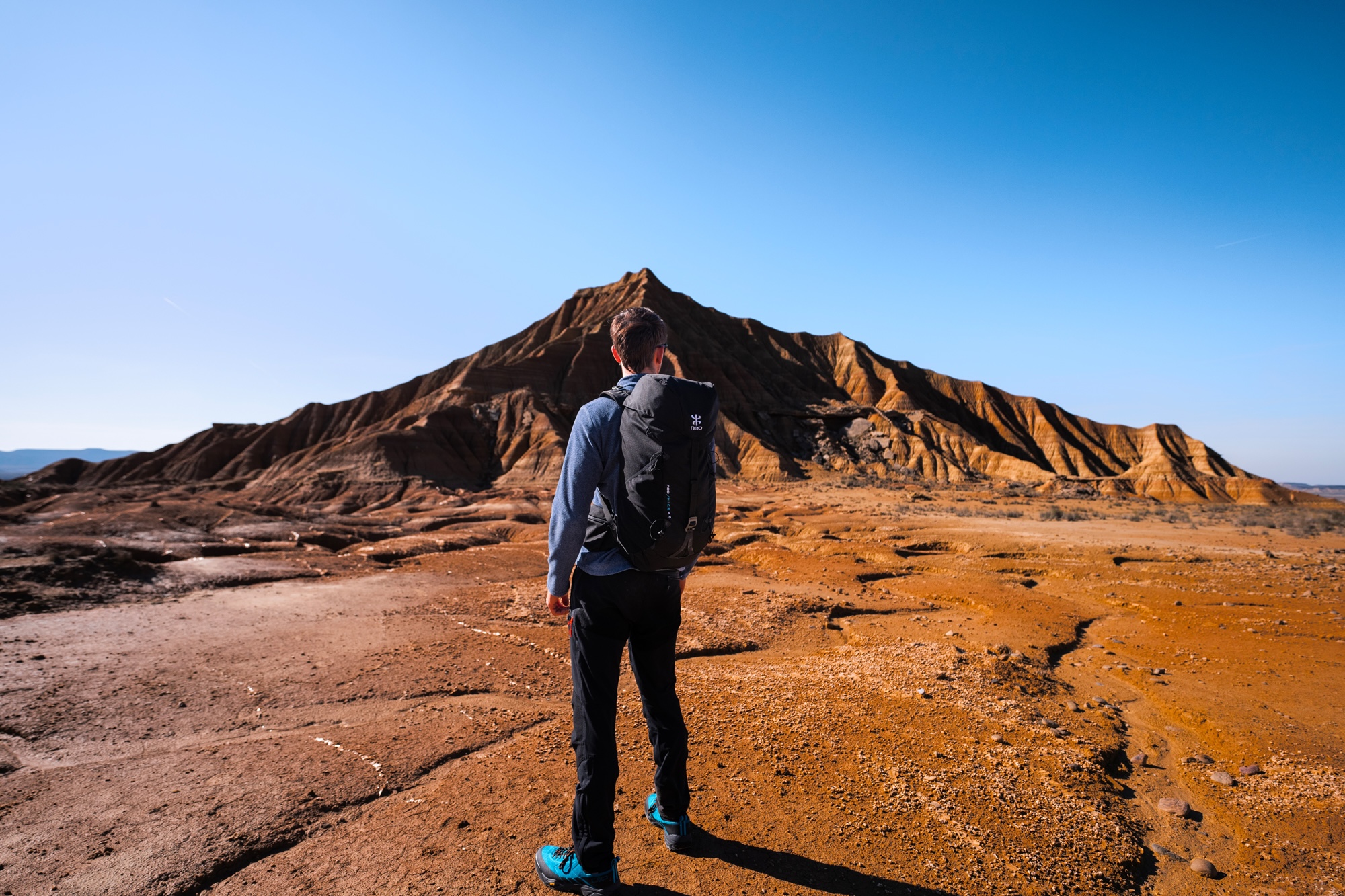 Homme debout de dos dans le désert avec le sac à dos Hike de NEO
